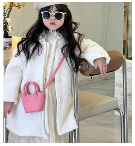 Detailed view of pink mini bucket bag with lychee texture and adjustable strap on child