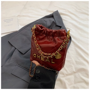 Detail der roten gesteppten Lackleder-Beuteltasche mit Goldkette und Kamelien-Anhänger
