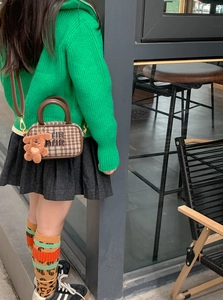 Close-up of kids checkered handbag with brown leather handles and a cute plush bear charm