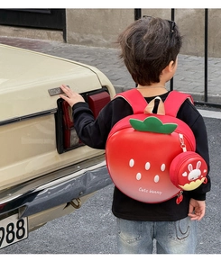 Detailed back view of a 3D strawberry kids backpack with a cute bunny hanging purse