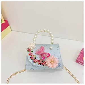 Detailed view of kids' blue floral handbag with pink butterfly and pearl handle strap
