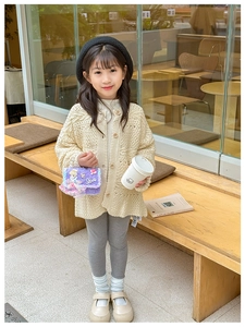 Fillette en cardigan en maille beige avec un sac à main princesse Cendrillon violet