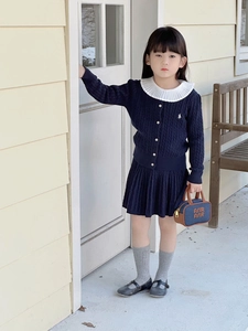 Detail of girls navy knit cardigan with cable pattern and white ruffles polo collar