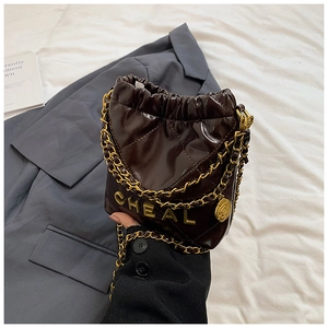 Detailaufnahme der braunen Stepp-Beuteltasche mit Goldkette und Kamelien-Anhänger