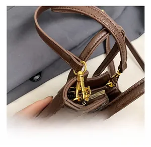 Detailed macro view of high-quality golden metal swivel hooks and brown litchi leather texture