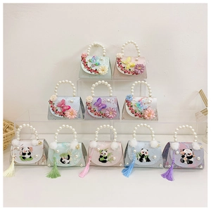 Detail of cute panda embroidery with silk tassels and pearl handles on mini handbags