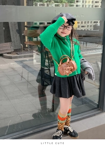 Detail einer braunen Mini-Boston-Tasche mit süßem Teddybär-Anhänger auf grünem Strick