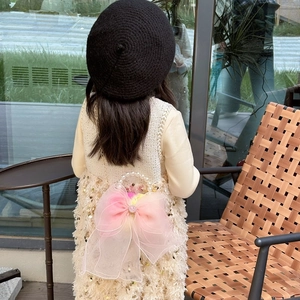 Kids sequin handbag with pink organza bow and pearl handle worn by a girl