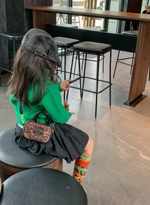 Mini leopard print crossbody bag styled with a green knit sweater and denim cap for kids