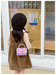 Detail of lavender mini bag featuring large pink bow and elegant pearl handle strap