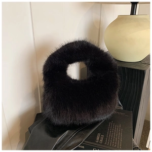 Vue artistique d'un sac à main en peluche noire duveteuse sur un livre chic