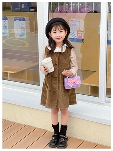 Detailed shot of brown corduroy girl dress with lace collar and pearl handle bag