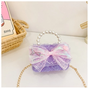 Détail du sac enfant en dentelle violette avec nœud rose et poignée en perles dorées