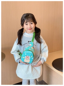 Detail view of a blue kids' crossbody bag with a cute Capybara print on a child model