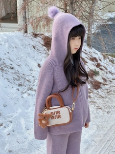 Close-up of kids crossbody bag with Arir embroidery and plush bear charm on snow
