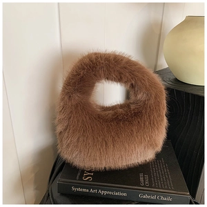 Détail artistique d'un sac à main en peluche marron chaud posé sur un livre noir