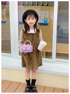 Toddler girl wearing vintage corduroy dress holding a mini purple pearl bow handbag