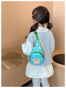 Detail view of mini blue Capybara kid crossbody bag with green strap on child back