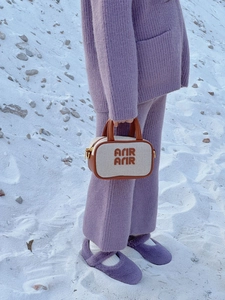 Mini cream crossbody bag with brown leather trim and embroidery on a purple knit outfit