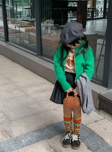Kinderoutfit Detail mit brauner geprägter Handtasche und grüner Strickjacke auf der Straße