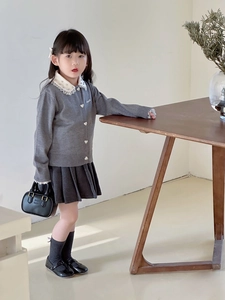 Detail der grauen Strickjacke mit Spitzenkragen und gesteppter Kinderhandtasche
