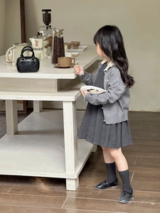 Detail der grauen Strickjacke mit Spitzenkanten und Faltenkleid für Kleinkinder