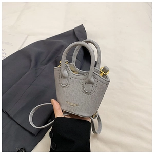 Mini grey bucket bag with lychee texture held by hand showing micro scale and gold text
