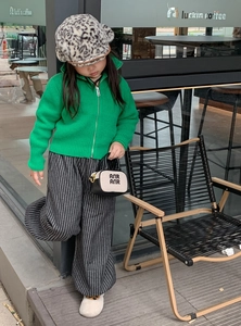 Outdoor street style shot of kids fashion set with green knit cardigan and leopard hat
