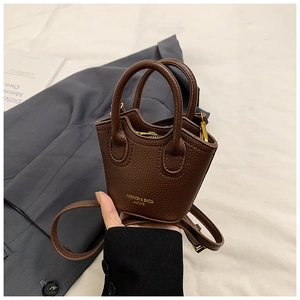 Detail of dark brown pebble leather mini bucket bag with gold hardware and strap