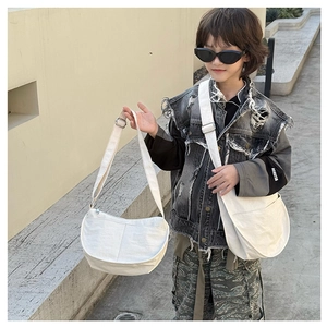 Detailed outdoor shot of a beige canvas crescent bag with adjustable strap for kids