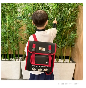 Detail of child wearing a black and red color-block backpack with cute cartoon bear print
