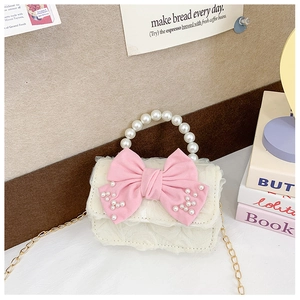 Detail of child mini bag with pink bow, pearl handle and gold chain strap