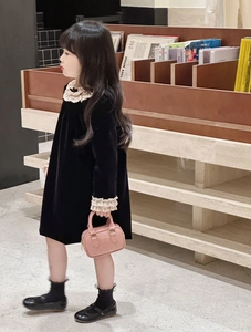 Details von schwarzem Samtkleid für Mädchen mit Rüschen und kleiner rosa Handtasche