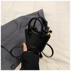 Detail of black mini litchi leather bucket bag with gold hardware and removable strap