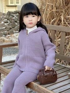 Detail eines lila gestrickten Kinder-Sets mit einer kleinen braunen Boston-Handtasche
