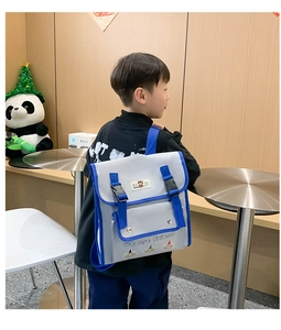 Detail view of child wearing the gray and blue bear backpack with buckle closure