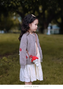 Détail d'un sac champignon au crochet fait main avec un cardigan en tricot pour enfants