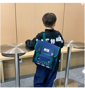 Detail view of the navy and green kids backpack worn by a child in a minimalist room