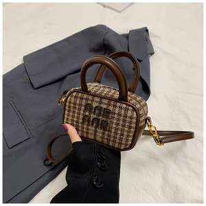 Close-up of retro plaid mini handbag with leather straps and gold metal hardware