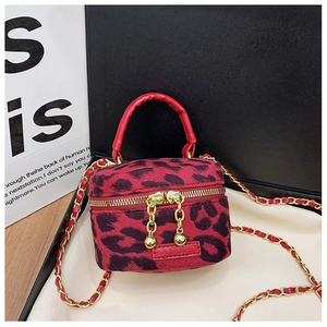Detail of red and black leopard print cylindrical bag with gold zipper and chain strap