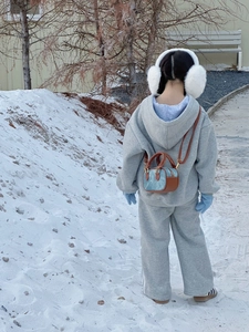 Schneeszene im Freien mit grauem Winteroutfit für Kinder und einer Mini-Umhängetasche