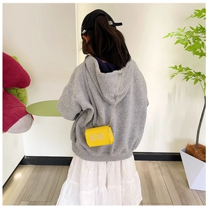 Detail showing a yellow crossbody bag for girls with a pearl bow and golden chain strap