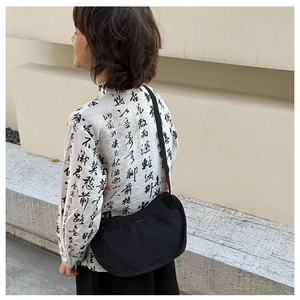 Outdoor shot of a black nylon crescent crossbody bag with an adjustable shoulder strap