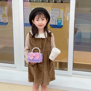 Girl's purple plush handbag with pink bow and pearl handle shown in an outdoor setting