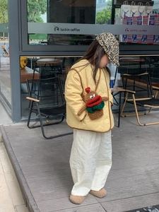 Close-up of a kids yellow quilted vest and a funny brown knit crossbody bag with red lips