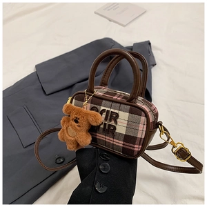 Detail of mini plaid handbag featuring a brown plush bear charm and leather strap