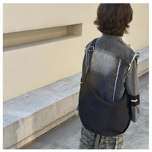 Kid model wearing a black crescent dumpling shoulder bag in an urban street style setting