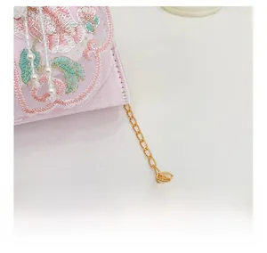 Détail de broderie florale rose et chaîne en métal doré sur sac pour filles