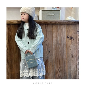 Detail of grey mini kids crossbody bag with yellow TOCHASO CUTE text on wooden table