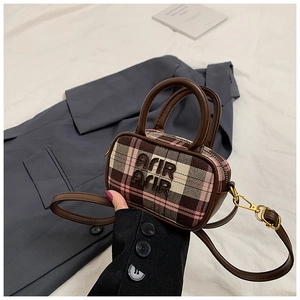 Detail of mini plaid handbag in brown and pink fabric with leather handles and gold clips